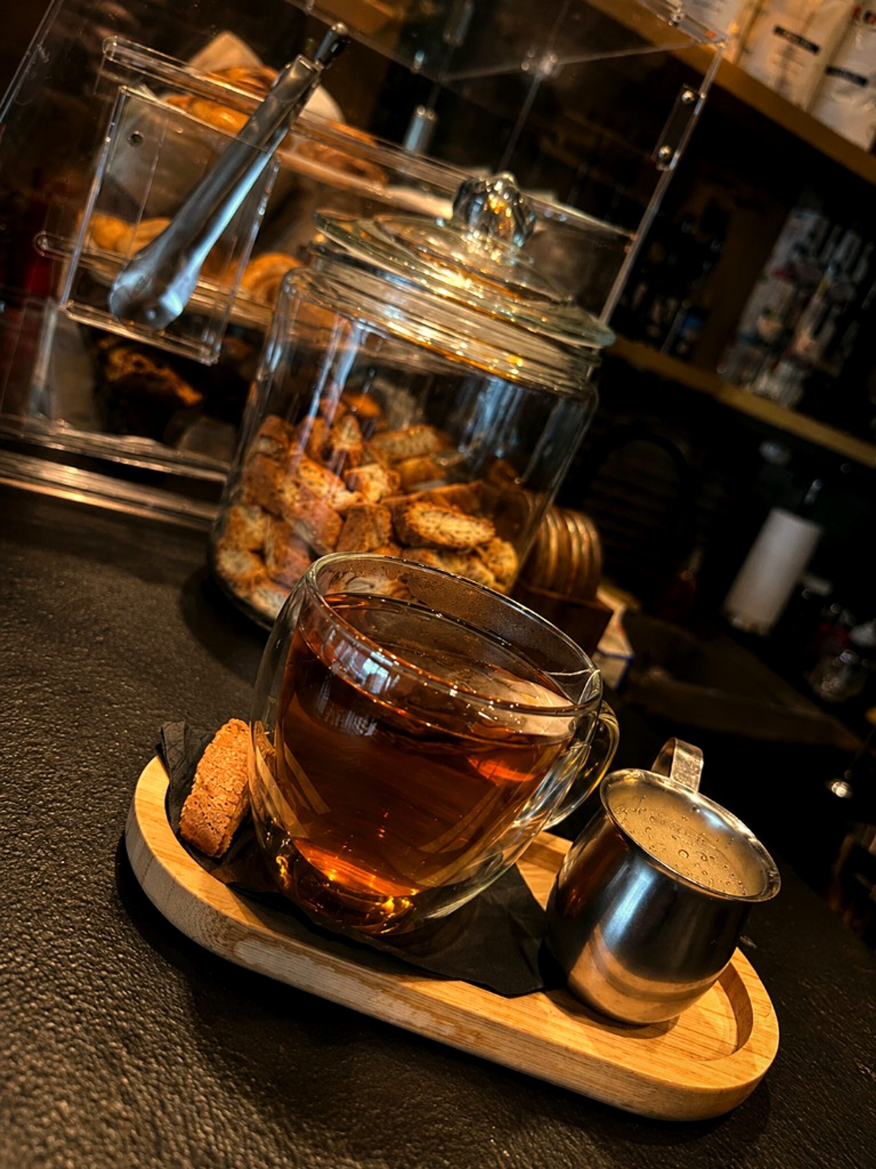 Tea served with biscotti on a wooden tray at One Gram Coffee Bar